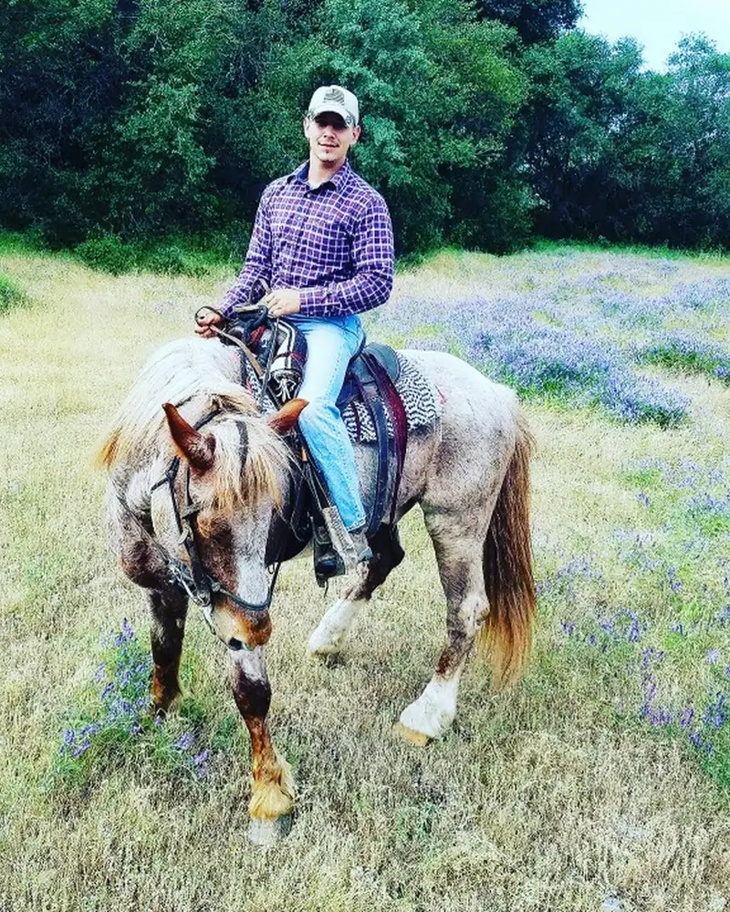 Zachary Leyden on a roan horse in a field of wildflowers